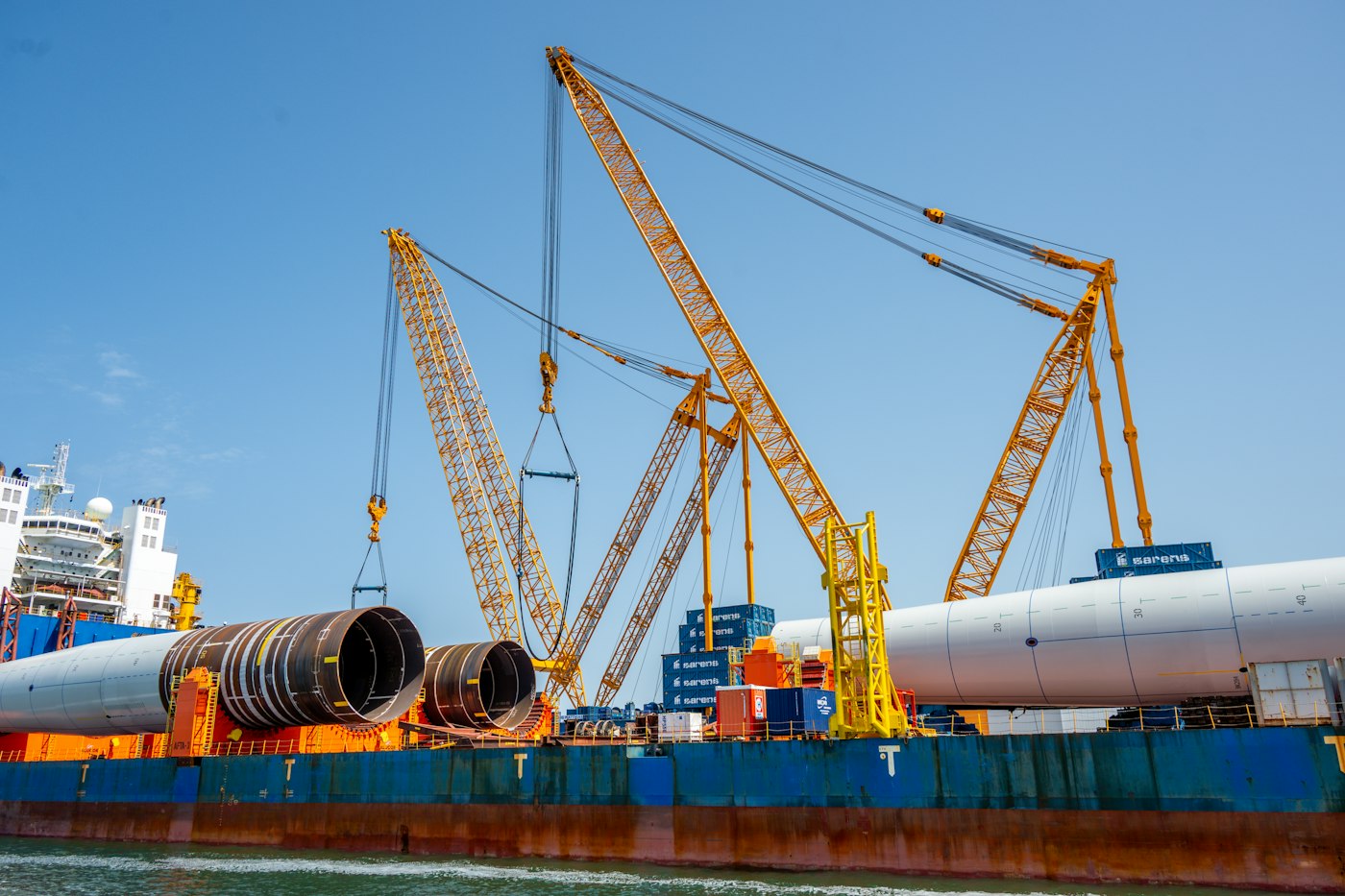 Pipe sections lifted by cranes